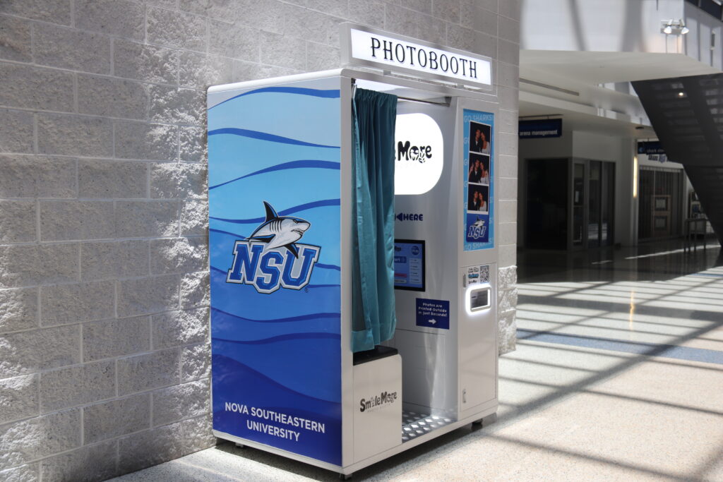SmileMore vending photo booth at NSU in Davie, FL, with NSU Sharks wrap, light-up PHOTOBOOTH sign and printed photo strips